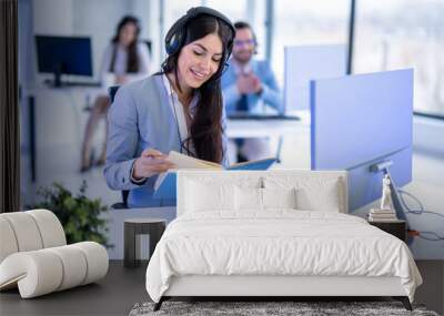 Smiling female support center agent checking schedule in notebook at her workplace in office Wall mural