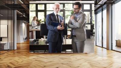 Two businessmen in formal suits discussing documents on a meeting in office Wall mural