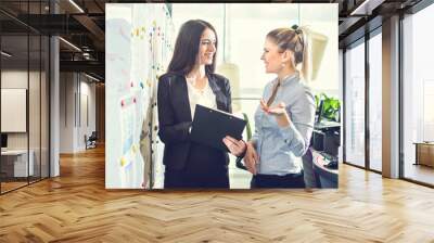 Two businesswomen talking to each other in the office. Wall mural