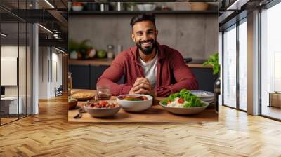 Young fit man having healthy breakfast at home, with a lot of fresh vegetables on kitchen table. Handsome indian man starting day with healthy meal. Wall mural