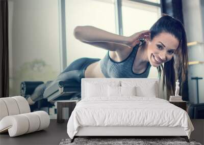 Young fit woman performing back-extension over exercise machine at gym Wall mural