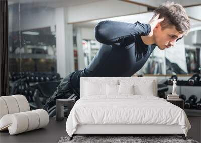 Young handsome fit man performing hyperextension exercise on roman chair at gym. Wall mural