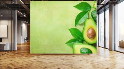 Fresh Green Avocado Halves with Leaves on Green Background Wall mural