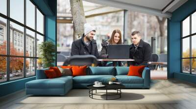 Group of students or young business people is sitting in an outdoor caffe and using laptop. Wall mural