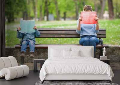 Little boy and his mother sitting on a park bench reading books Wall mural