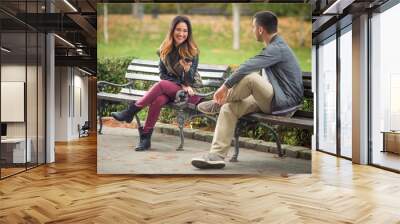 Two young people sitting on benches in a park and talking Wall mural