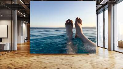 Male legs, feet with fingers spread out in a beautiful blue wet azure natural clear water against a blue sky and horizon line in a tropical warm sea resort. Wall mural