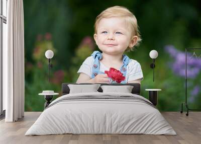 Portrait of a one-year-old girl with blue eyes holding a rose Wall mural