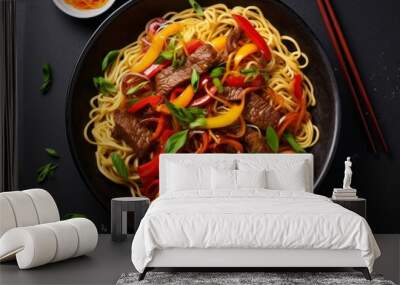 Close up top view stir fry noodles with vegetables and grilled beef in black bowl on dark table, slate background. Wall mural