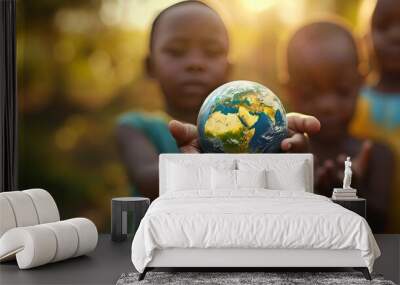 Diverse Group of African Children Unitedly Holding a Small Earth Globe Outdoors with Warm Sunlight Illuminating from Behind Wall mural