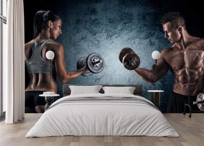 Athletic man and woman with a dumbells. Wall mural