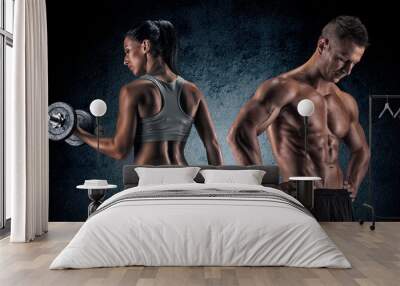 Athletic man and woman with a dumbells. Wall mural