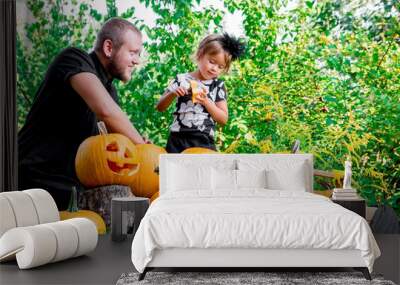 Daughter near father who pulls seeds and fibrous material from a pumpkin before carving for Halloween. Prepares  jack-o-lantern. Decoration  party. Happy family. Little helper. Wall mural