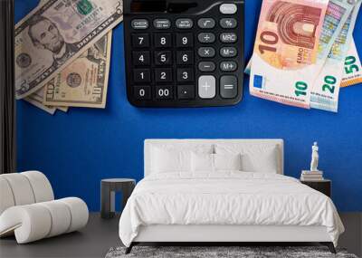 Flat lay or top view of calculator, money dollars and euro on blue background Wall mural