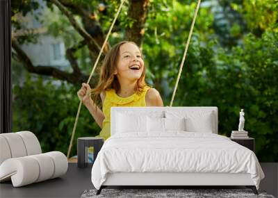 Happy barefoot laughing child girl swinging on a swing in sunset summer day Wall mural