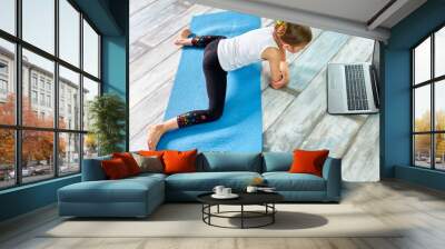 Little cute girl in sportswear on blue mat practicing gymnastics at home Wall mural