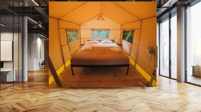 Interior of Cozy open glamping tent with light inside during dusk. Luxury camping tent for outdoor summer holiday and vacation. Lifestyle concept Wall mural