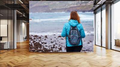 Woman tourist with backpack standing on the quay and watching the ocean in Puerto de la Cruz, The Canary Islands, Spain Wall mural