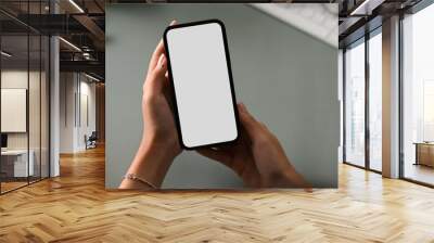 A businesswoman holding smartphone over her office desk. Wall mural