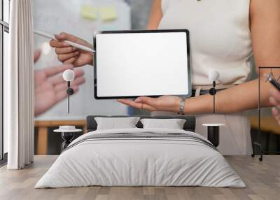 A close-up of a businesswoman showing a digital tablet to her team members during the meeting. Wall mural