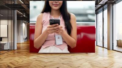 A cropped image of a happy Asian businesswoman chatting on her smartphone while taking the sky train Wall mural