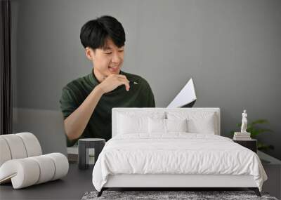 A handsome Asian man checks his meeting schedules in his personal planner book Wall mural