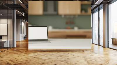 A white-screen laptop computer on a white kitchen tabletop in a modern green kitchen. Home workspace Wall mural