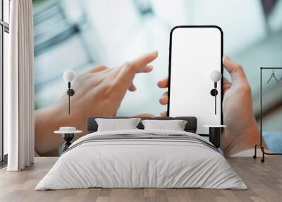 A woman holding a smartphone with a white screen mockup over a blurred cafe in background. Wall mural