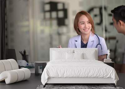 Asian female doctor using tablet computer and talking to male Asian patient Wall mural