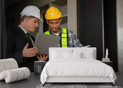 Asian male construction engineer working with a Caucasian businessman while inspecting the building. Wall mural