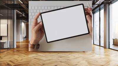 Businessman holding blank screen tablet above computer keyboard and supplies on white office desk Wall mural