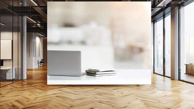 Close up view of simple workspace with laptop, notebooks, coffee cup and tree pot on white table with blurred office room Wall mural