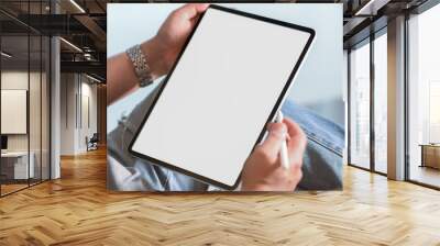 Cropped shot of a man sitting at modern living room and using vertical blank screen tablet Wall mural