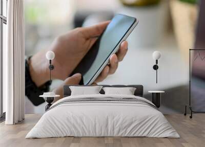 Cropped shot of a man using smartphone while working at workspace Wall mural