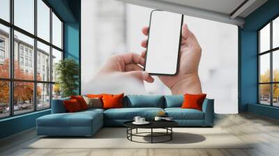 Cropped shot of businessman touching  blank screen smartphone with blurred office room Wall mural