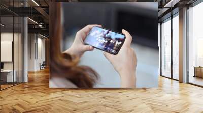 Cropped shot of female hand holding mobile phone playing video stream online Wall mural