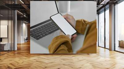 Female freelancer working with mock-up smartphone and laptop on simple workspace Wall mural