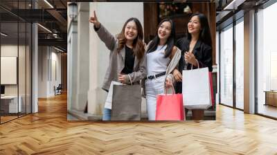 Group of fun Asian girl friends are enjoying shopping in the city during their abroad trip together. Wall mural