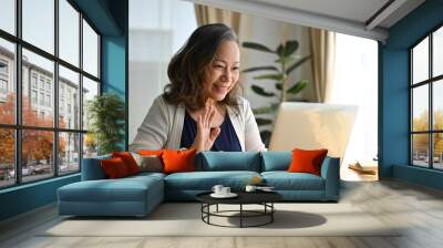 Happy asian aged woman using laptop computer to video call with her family. Wall mural