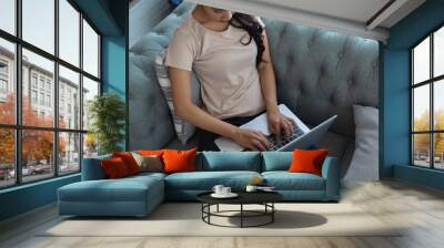 Overhead shot of female using laptop on her lap while sitting sofa Wall mural