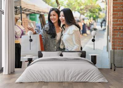 Overjoyed Asian female travelers with their shopping bags enjoy shopping Thai-local products Wall mural