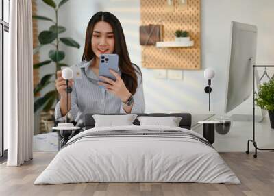 Smiling Asian businesswoman registers for online payment services on a mobile banking app Wall mural