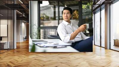 Successful Asian businessman thinking and planning his business while having coffee Wall mural