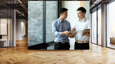 Two asian businessmen working together on a digital tablet in an office Wall mural