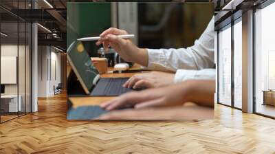 Two female workers consulting on their project while working with mock-up tablet on wooden table Wall mural