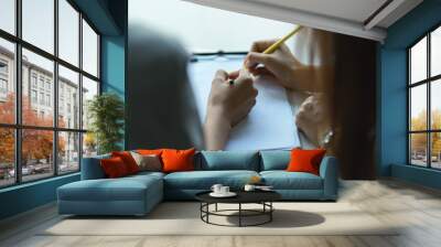 Two people hand writing on blank paper on clipboard while consulting on their work Wall mural