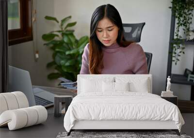 young Asian woman calculating her tax and monthly bills, trying to save her budget for her saving Wall mural