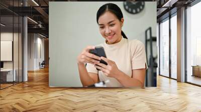 Young beautiful woman using smartphone at her desk Wall mural