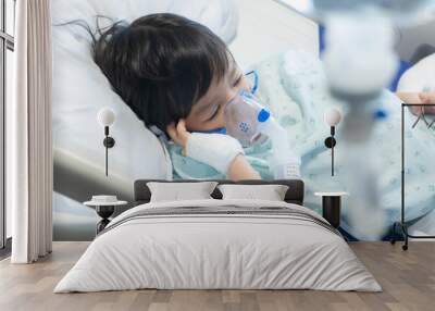 an Asian toddler boy has Cold or Flu or influenza or asthma or pneumonia disease and need nebulizations,Sick boy rest on patient bed in hospital and has inhalation therapy by the mask of inhaler.Sick  Wall mural