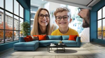 Cheerful family of three enjoying their visit to the opticians office while wearing stylish glasses and sharing smiles together Wall mural